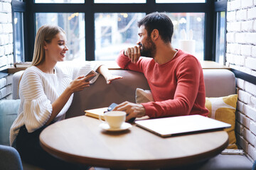 Fototapeta na wymiar Happy young couple enjoying coffee break in coffeehouse in cozy cafe