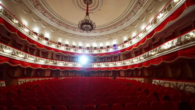 Empty theater or opera house. Red chairs in theater hall. Panoramic view on beautiful interior. No audience because of pandemic.