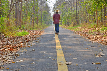 Walking man on yellow line of black road in the forest