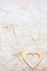 Heart shape made of wood, on a light background with garland lights and copy space. Minimalistic...