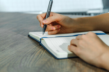 Female hands are writing in a notebook