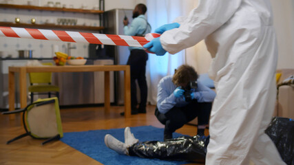 Forensic team investigating murder in apartment and taking photo of dead body