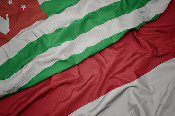 waving colorful flag of indonesia and national flag of abkhazia.