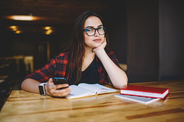 Thoughtful woman with book in cafeteria