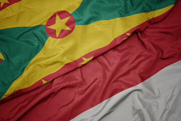 waving colorful flag of indonesia and national flag of grenada.