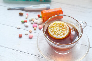lemon tea, pills and thermometer on table 