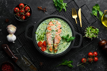 Salmon steak with creamy spinach sauce in a pan. Restaurant food. Seafood. Rustic style. Flat Lay.
