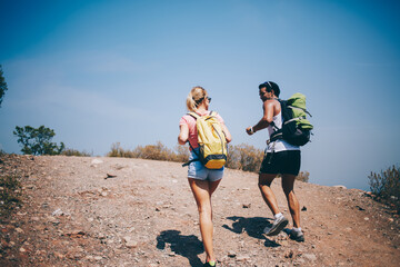 Traveling couple walking on empty road with backpacks