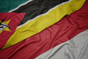 waving colorful flag of indonesia and national flag of mozambique.
