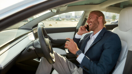 Laughing young businessman on driver seat in car