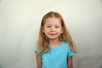 Fototapeta premium Cute little girl shows emotions on a white background in a T-shirt. Simple beauty. High quality photo