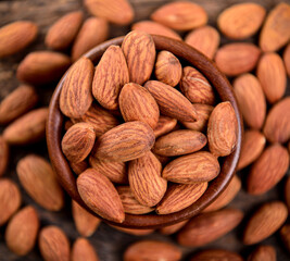 Almonds in wooden bowl on table.