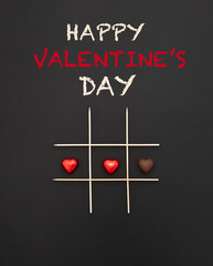 Happy Valentine's Day text. Game of tic-tac-toe with chocolate hearts with and without wrapper....