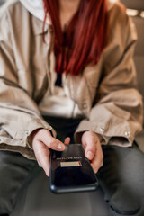 Close up of female hands holding mobile phone while sitting on back seat in the car. Low battery notification on the screen