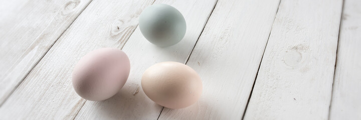 Easter eggs in tender colors on white vintage wood. Horizontal background for easter greetings with space for text
