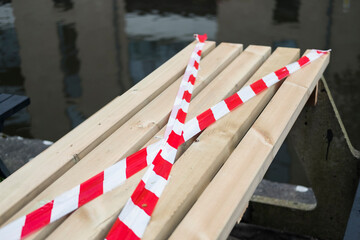 A table cordoned off with barrier hazard tape, do not cross red warning barrier, covering a closed restaurant bar stopping customers from using and sitting during the corona virus pandemic. 