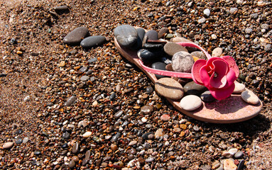 Flip-flops with sea stones on the beach. Sea background.