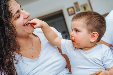 Boy eating  chocolate while playing with mom