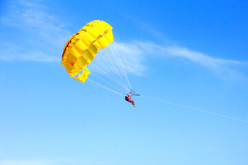 Yellow parachute in the sky. The man is flying by parachute.