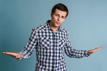 Confused young man doubting and shrugging shoulders
