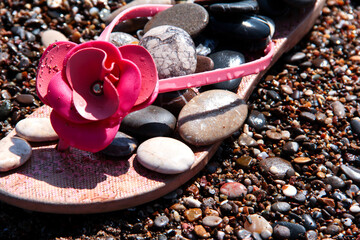 Flip-flops with sea stones on the beach. Sea background.