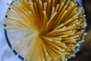 Spaghetti in a glass jar. The pasta is scattered on the table.