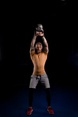 Fototapeta na wymiar bald tattooed athlete with a red beard raised a kettlebell over his head with both hands