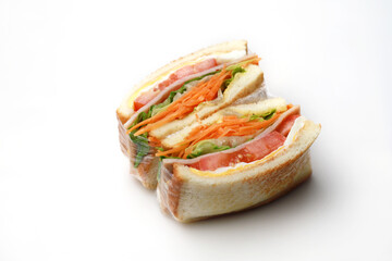 Sandwich with ham, egg, tomatoes, lettuce and toasted bread. High angle view isolated on white background.