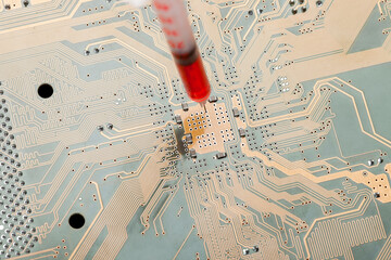 printed circuit board with contact paths and syringe with needle filled with red liquid, concept on theme of cospirology of vaccination and chipization of society given control to population.