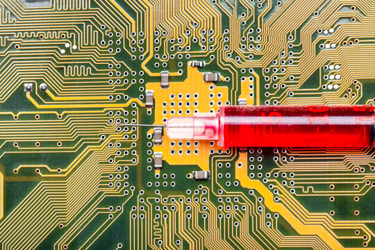 syringe with needle filled red medicinal product lies on silicone printed circuit board with contact tracks of electronic equipment of modern medicine vaccine cyber implantation treatment.