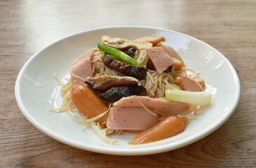 fried Chinese vegetarian rice noodles with slice pork sausage and bologna couple bean sprout topping cutting black mushroom on plate