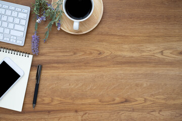 Top view above of Wooden office desk table with keyboard, coffee cup and notebook, phone with equipment office supplies. Business and finance concept. Workplace, Flat lay with blank copy space.