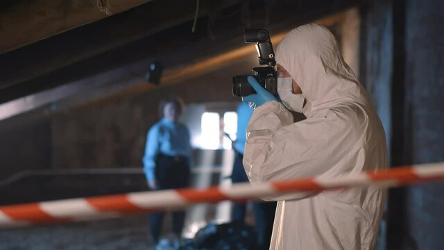 Forensic specialist with photo camera standing at crime scene