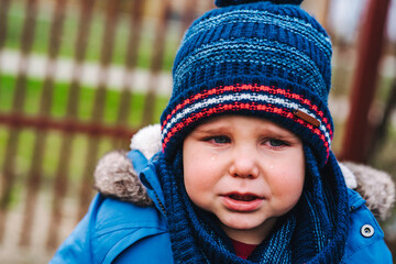 Boy being upset and crying in the park on a winter day