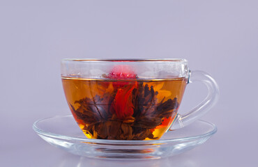 Exotic green flower tea in a glass cup on a gray background.