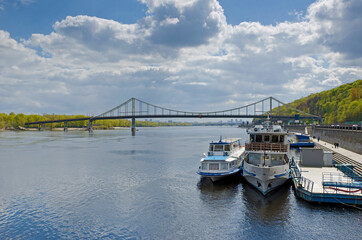 Footbridge Dnipro river panorama embankment with tourist boats Kyiv Ukraine