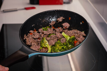 Skillet of ground beef stir fry with vegetables broccoli pepper and onion on an electric stove on high speed Cordoba Argentina