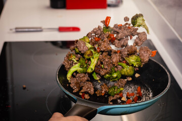 Skillet of ground beef stir fry with vegetables broccoli pepper and onion on an electric stove on high speed Cordoba Argentina