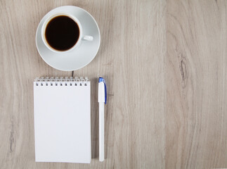 Notebook, pen and coffe, wooden background.