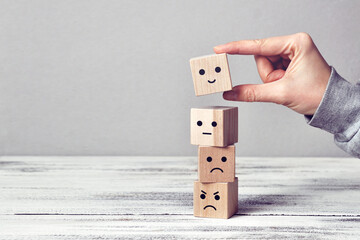 Wooden cubes with drawings of different emotions: sadness, anger, calmness, joy. Choosing joy in life
