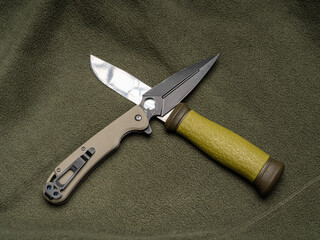 Pocket knife and fixed blade knife on a green olive background