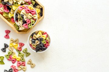 Fototapeta na wymiar Top view of coloured farfalle pasta in bowls