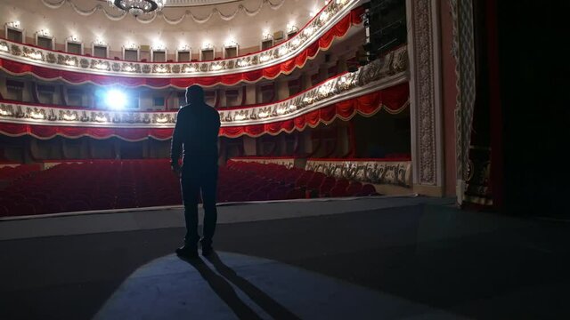 No people in theater auditorium. Actor has rehearsal in front of empty hall.