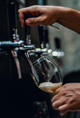 bartender hand at beer tap pouring a draught beer in glass serving in a restaurant or pub