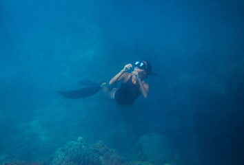 Woman in blue water, freediving photo. Freediver and coral reef landscape. Tropical island lagoon...
