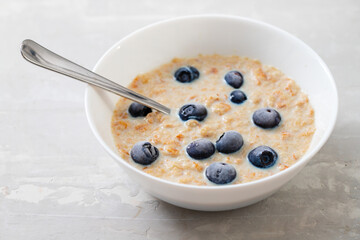 healthy wheat flakes with milk and blueberries in white bowl