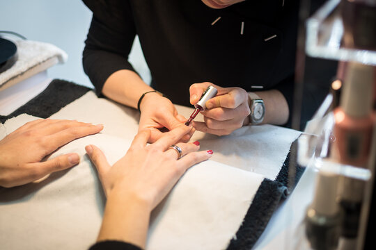 Soins en Salon de beaut&eacute; - Pose de vernis rouge sur une main de jeune femme