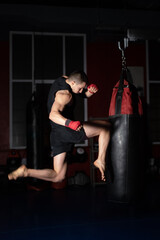 Kickboxing fighter Performing Jumping Air Kicks with Knee on Punch Bag. Caucasian Man Practicing...