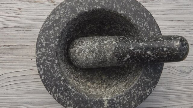 Top view of the male hands placing the grey stone mortar with a pestle on the table