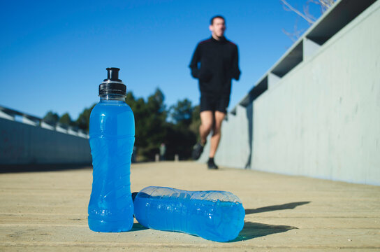 Blue isotonic drink with boy running in the background. Exercise concept. image with copy space